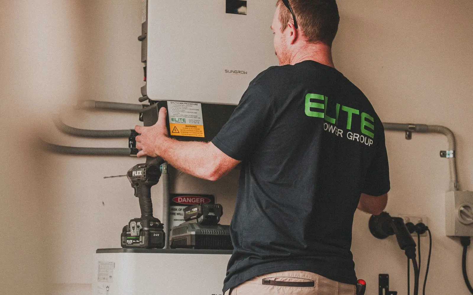 Batteriespeicher oder Wärmespeicher: gleiche Idee, andere Aufgabe – Batteriespeicher im Wohnhaus: Installation eines Heimspeichers Elektriker installiert einen wandmontierten Batteriespeicher in einem Wohnhaus