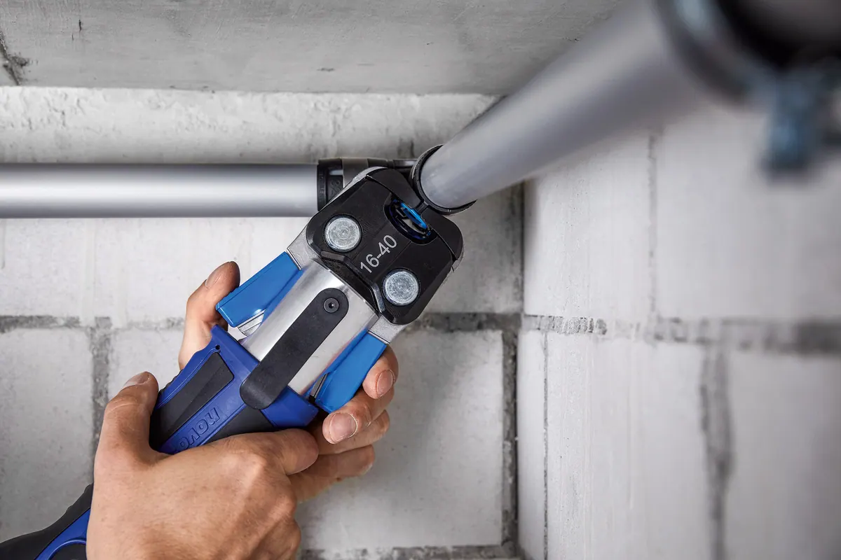 Geberit FlowFit: Eine blaue Pressbacke setzt seitlich an der Rohrverbindung an