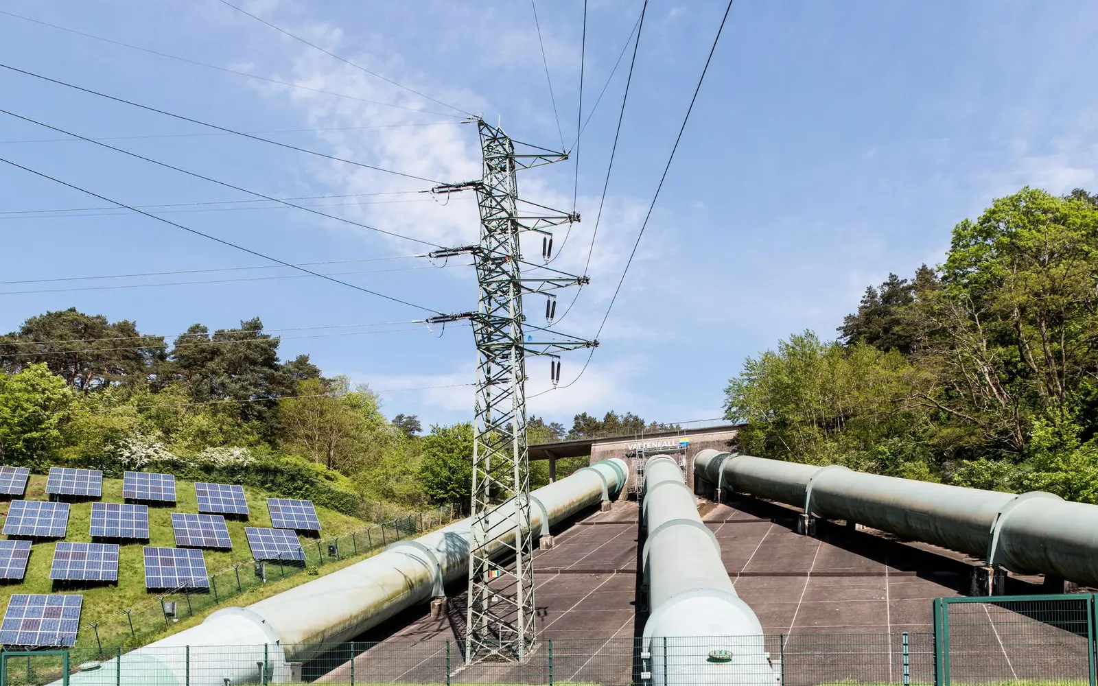 Österreich Q1/2026: 243 MW neue Photovoltaik, bei Wind kein Zubau – Netzanschluss für Photovoltaik und Windenergie in Österreich Strommast und Leitungen neben einer Photovoltaikanlage als Symbol für den Netzanschluss