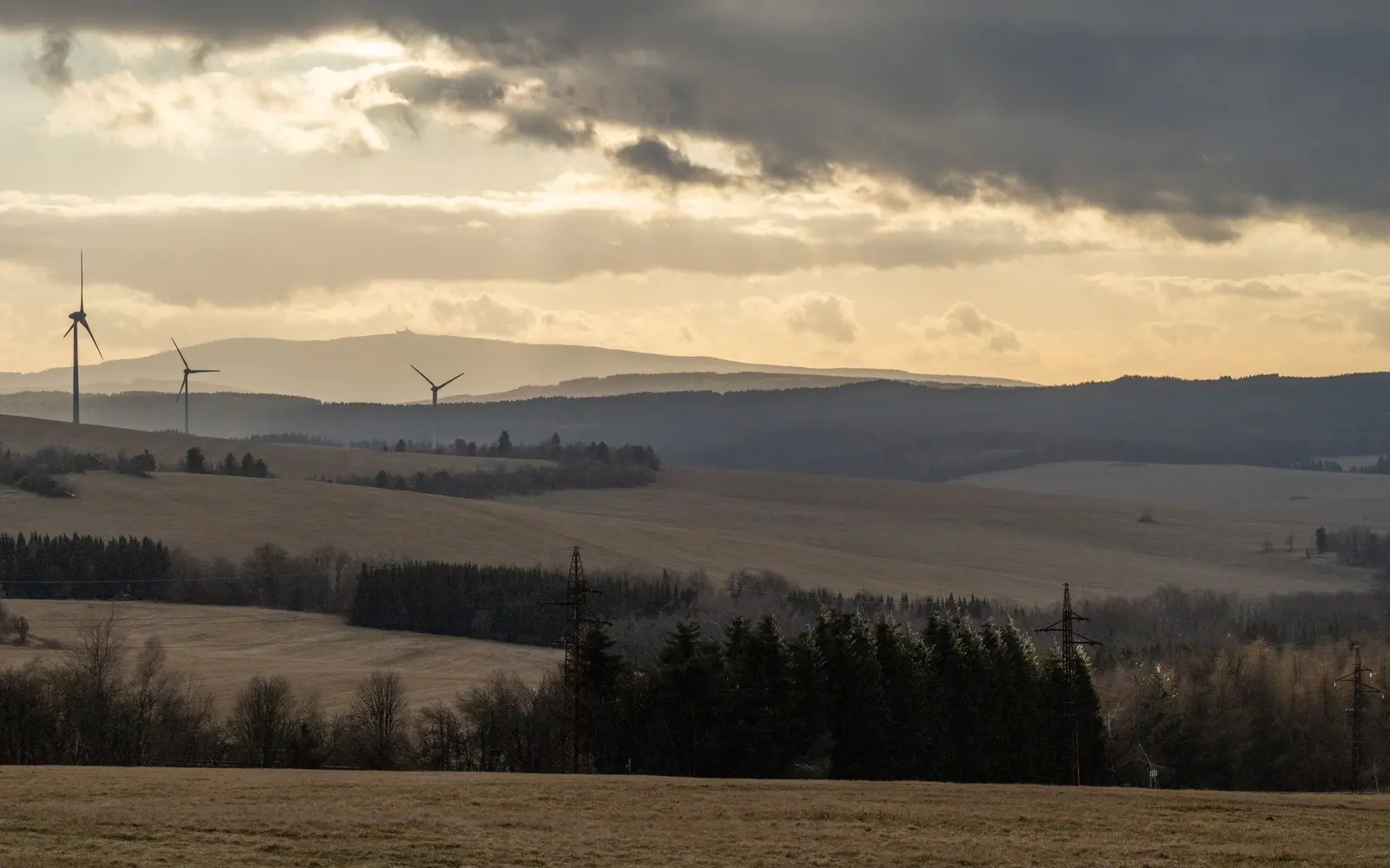 Windenergie 2025: mehr installierte Leistung trotz schwachem Windjahr – Windenergie 2025: Windpark in einer offenen Landschaft Mehrere Windkraftanlagen in einer hügeligen Landschaft bei tief stehender Sonne